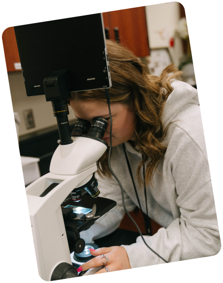 woman looking through a microscope