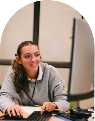 teen girl typing on a keyboard with a pencil in her hand